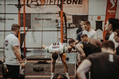 Group of athletes engaging in a competitive CrossFit workout at a gym with emphasis on strength and teamwork.