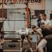 Group of athletes engaging in a competitive CrossFit workout at a gym with emphasis on strength and teamwork.