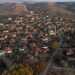 Aerial view of a traditional Turkish village surrounded by hills, showing red-roofed houses, narrow streets, and rural landscape in autumn